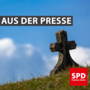 Bild eines einsamen Kreuzes auf grüner Wiese. Text: "Aus der Presse"